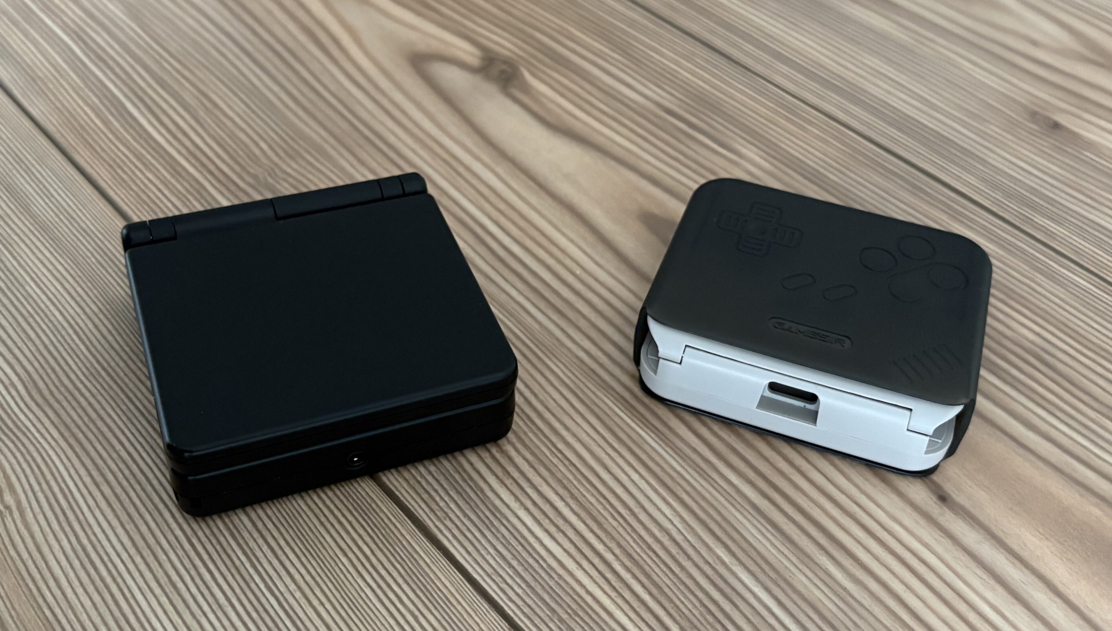 Anbernic RG34XXSP und GameSir Pocket Taco zugeklappt auf Holzboden