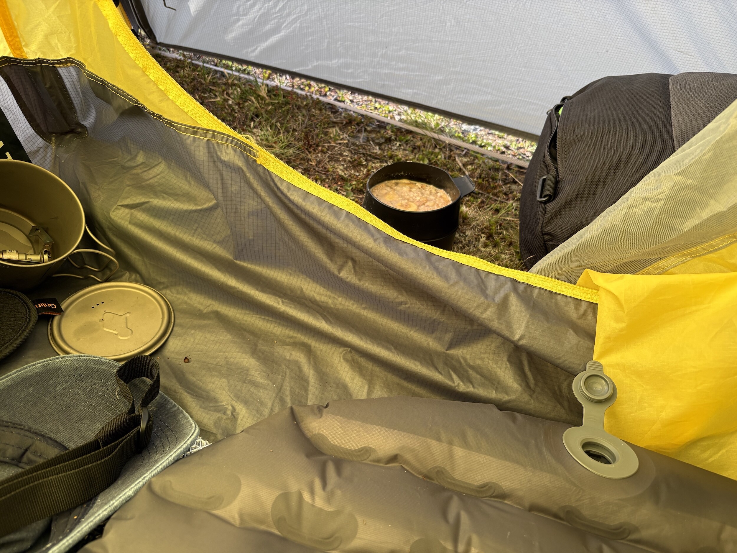 Zeltinnere mit Campinggeschirr und einer Schüssel mit Essen mit Porridge nach dem Sturm