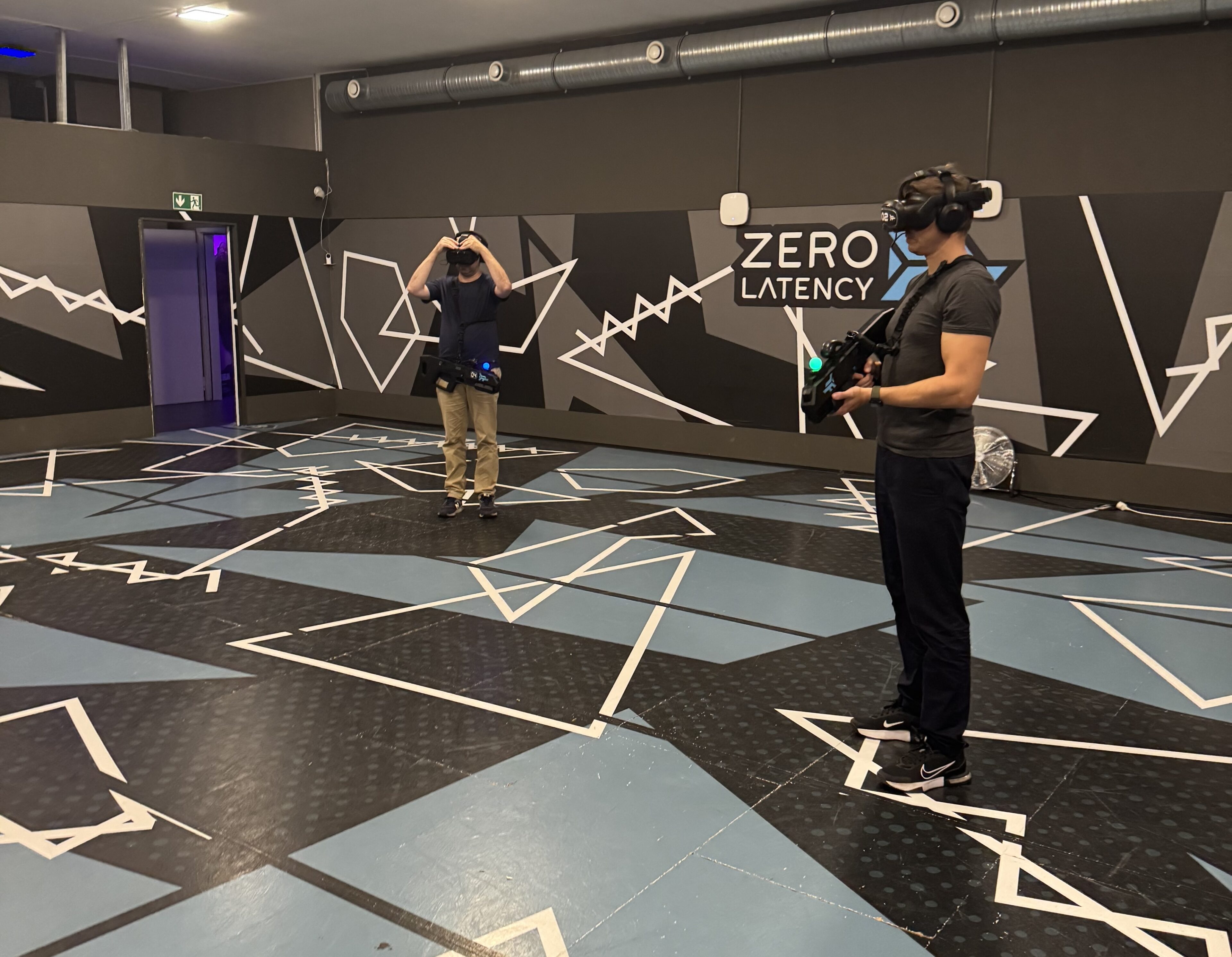 Zwei Männer mit VR-Headsets und Controllern in einer Zero-Latency-VR-Spielhalle